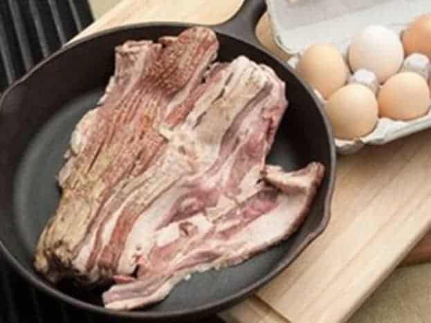 US wellness beef whole30 bacon in a cast iron skillet with eggs