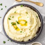 an overhead shot of mashed potatoes with wasabi and a gold spoon on a grey board