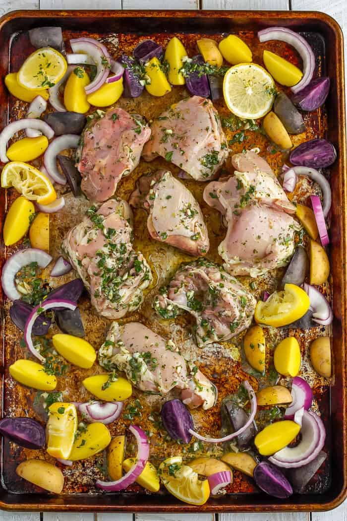 a sheet pan with greek chicken thighs, potatoes, and onions