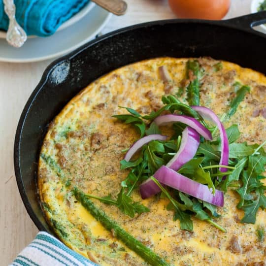 a paleo frittata in a cast iron skillet with greens and onion
