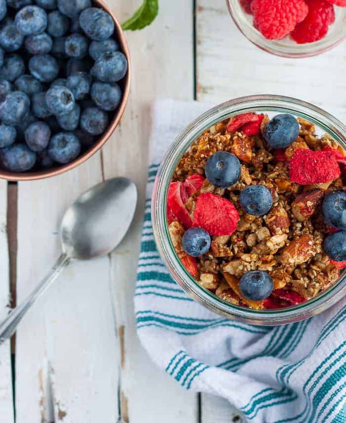 a glass bowl of paleo granola with blueberries and freeze-dried strawberries.