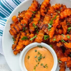 a plate of baked butternut squash fries with a dipping sauce