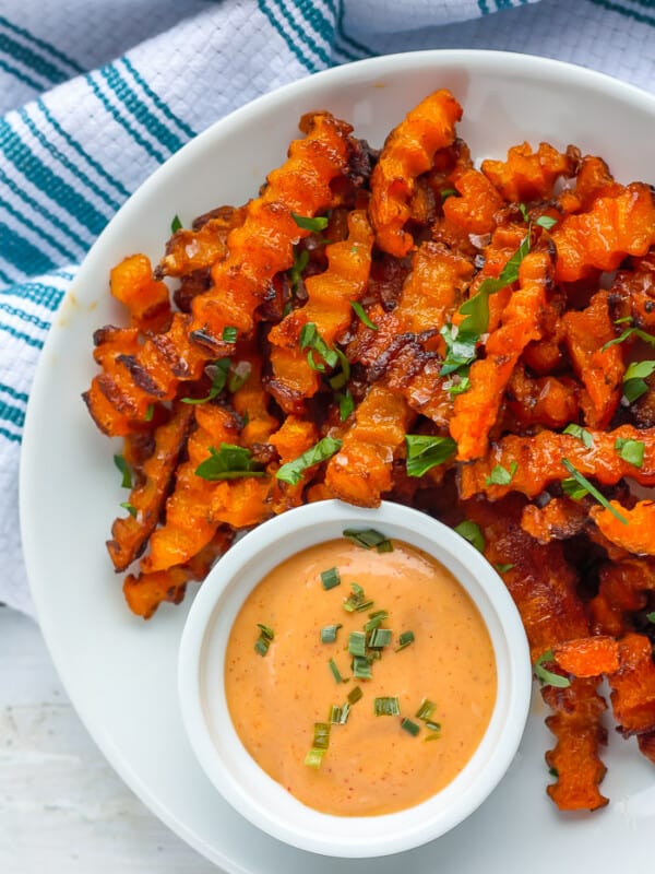 a plate of baked butternut squash fries with a dipping sauce