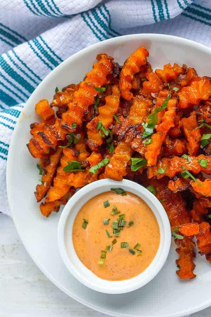 a plate of baked butternut squash fries with a dipping sauce 