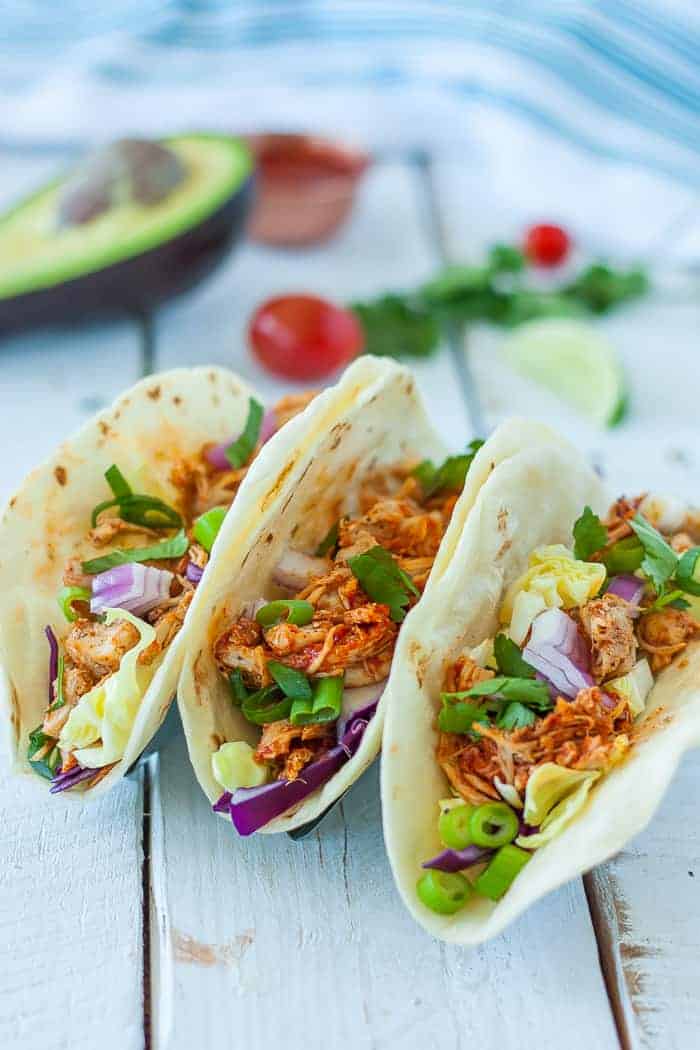 three tortillas with pressure cooker chicken taco meat and other toppings