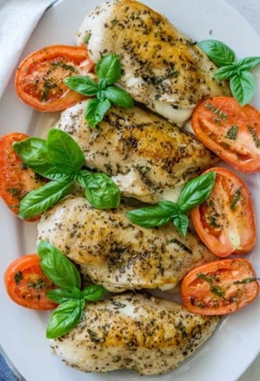baked stuffed chicken breasts with tomatoes and basil on a white dish