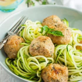 a bowl of zoodles with greek turkey meatballs and basil