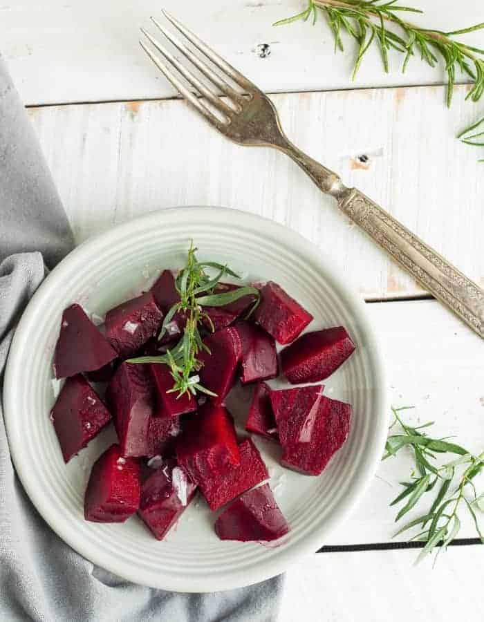 pressure cooker beets on a plate with fresh thyme and a fork