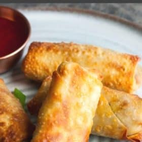 Air fryer egg rolls on a plate with dipping sauce