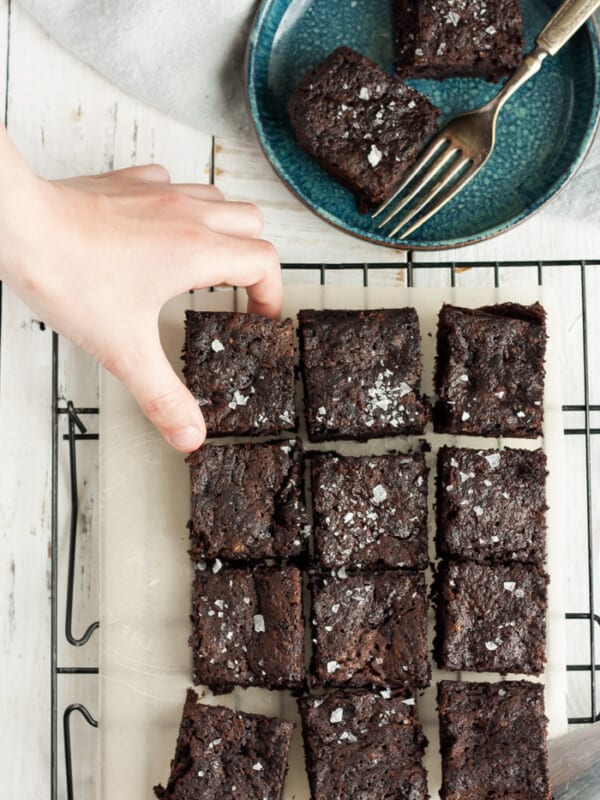 a hand reaching for a brownie on a baking rack