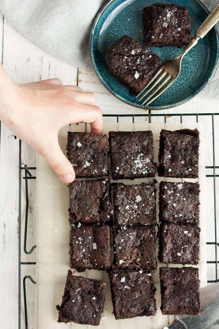a hand reaching for a brownie on a baking rack