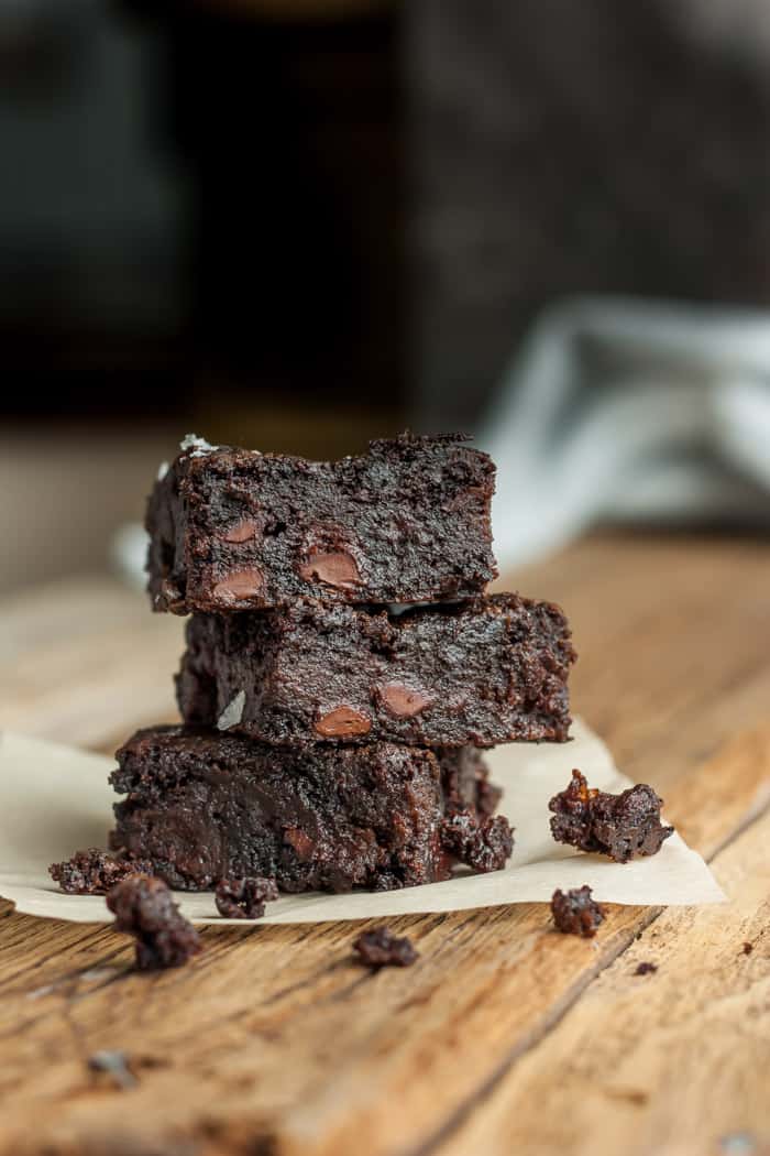 Three almond flour brownies stacked on a piece of parchment