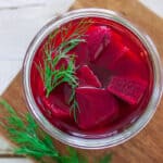 a glass jar of refrigerator pickled beets topped with fresh dill