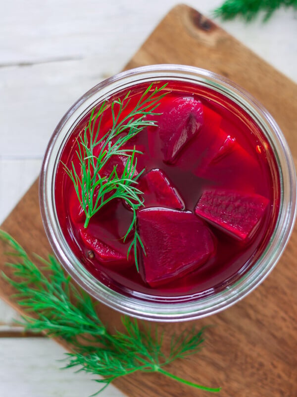 a glass jar of refrigerator pickled beets topped with fresh dill