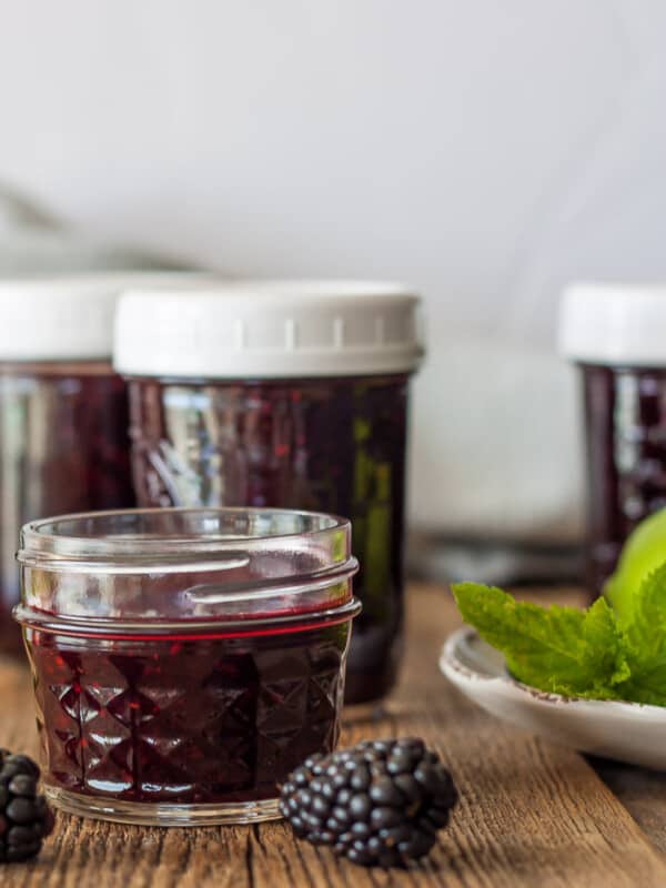 four jars of blackberry freezer jam with mint and blackberries