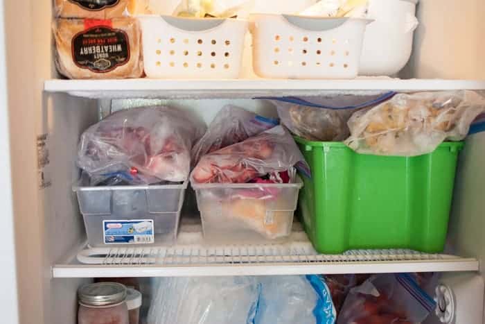 a freezer shelf with bins of frozen fruit