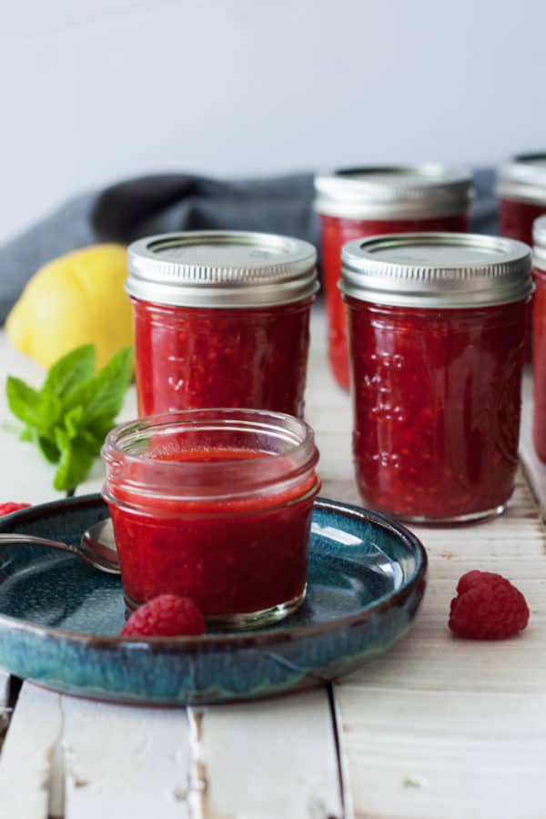 jars of homemade raspberry freezer jam with lemon and mint
