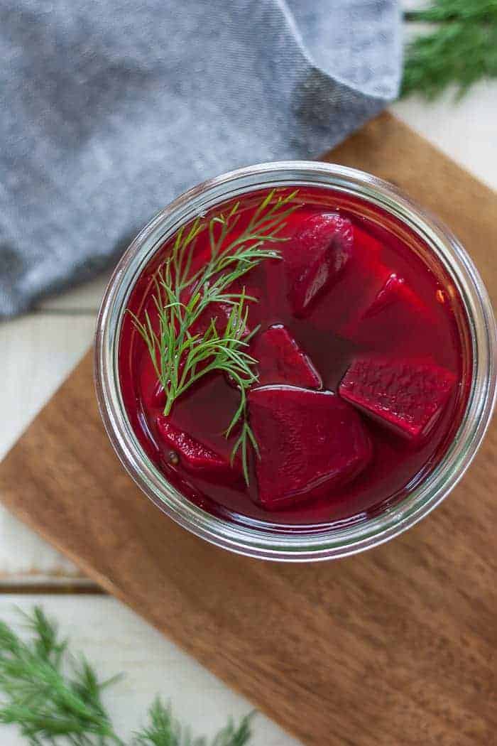a jar of pickled beets on a wooden cutting board