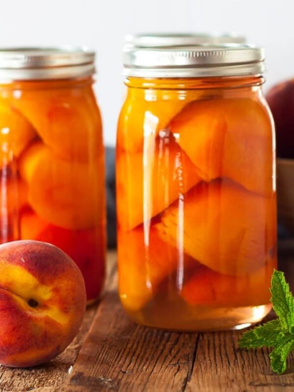 Jars of canned peaches on a wooden board