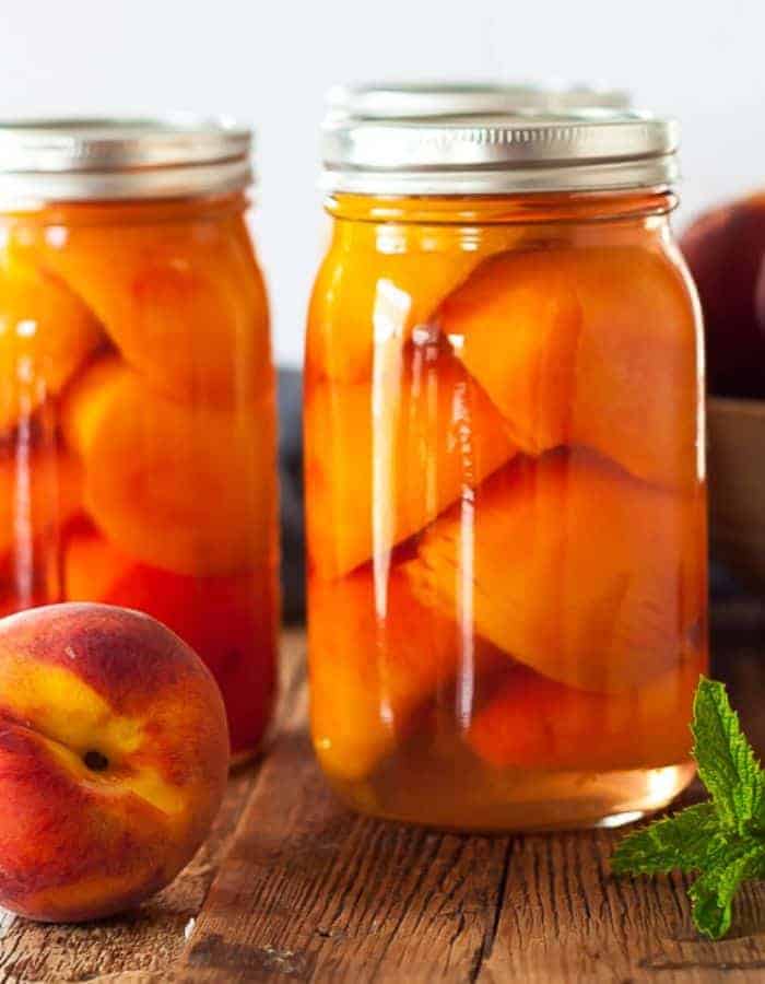 Jars of canned peaches on a wooden board