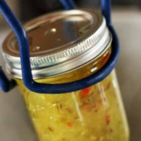 canning tongs holding a canning jar of glass relish