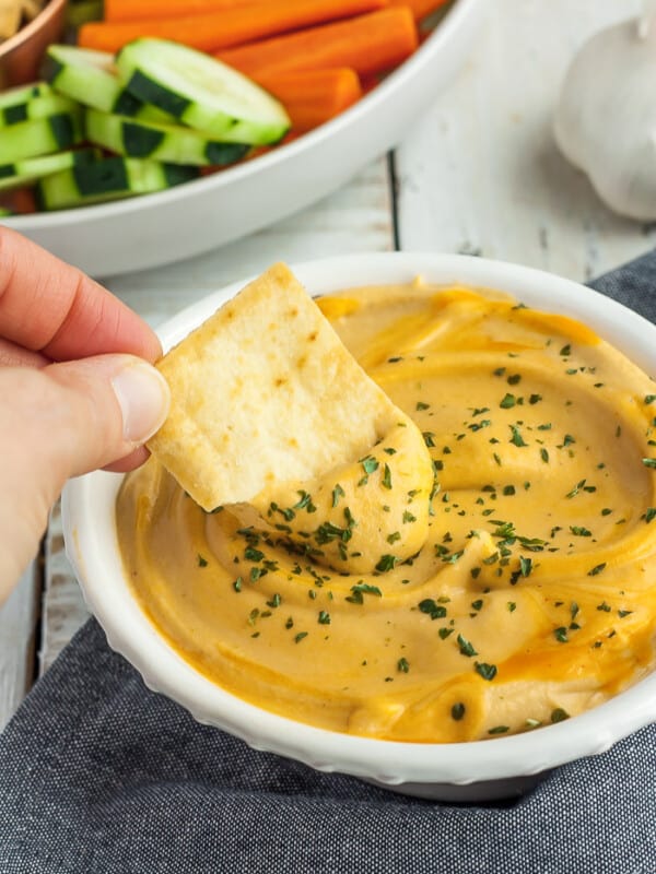 a pita chip being dipped into a bowl of buffalo hummus