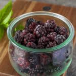 a bowl of frozen blackberries with a sprig of mint