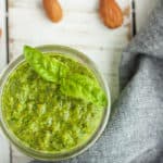 a small jar of vegan pesto with almonds and a grey cloth