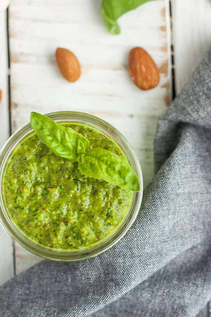 a small jar of whole30 pesto with almonds and a grey cloth