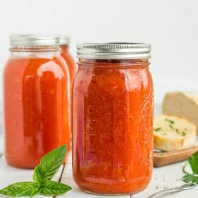canning jars of tomato soup with herbs and garlic bread