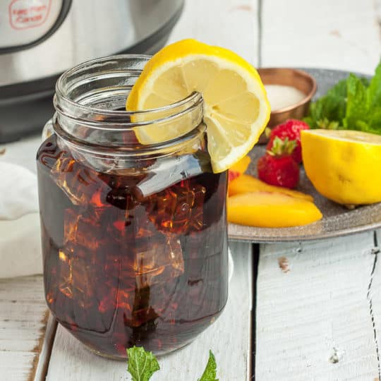 a jar of iced tea with lemon and a plate of garnishes