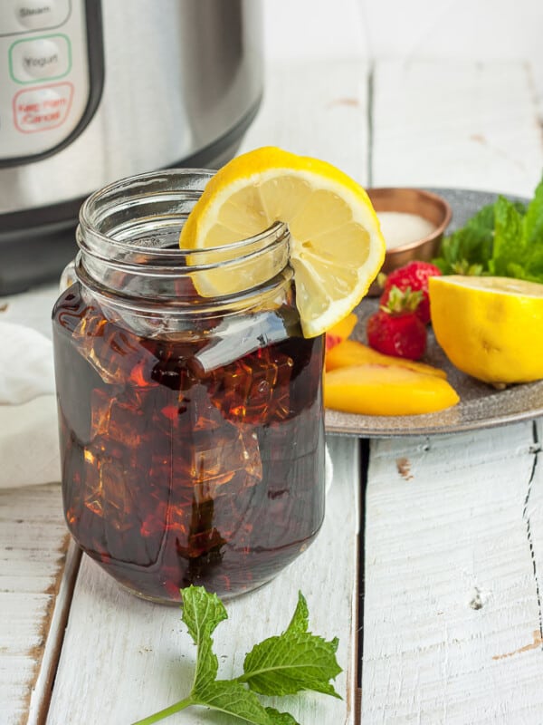 a jar of iced tea with lemon and a plate of garnishes