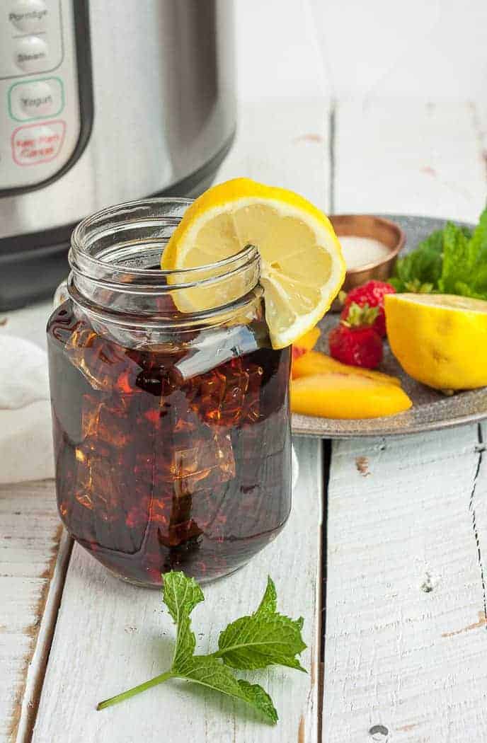 a jar of iced tea with lemon and a plate of garnishes 