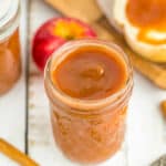 a jar of apple butter with fresh apples and cinnamon sticks