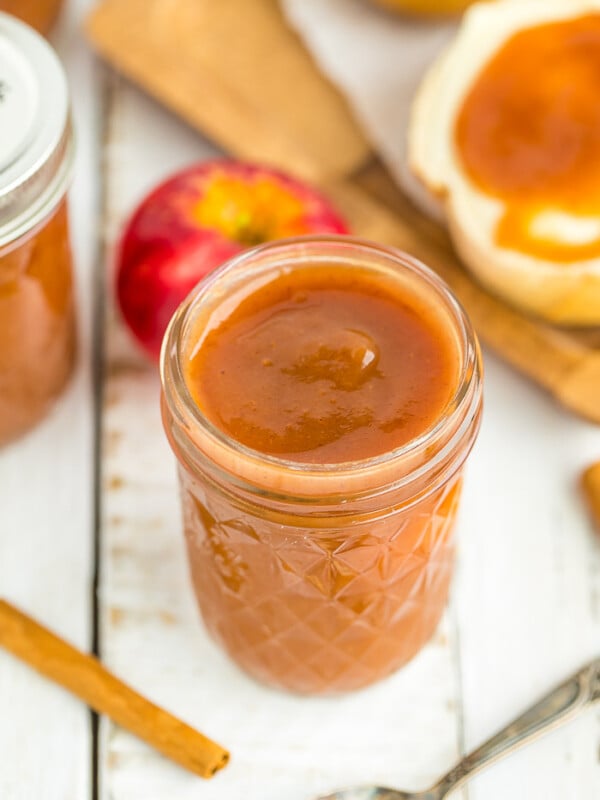 a jar of apple butter with fresh apples and cinnamon sticks