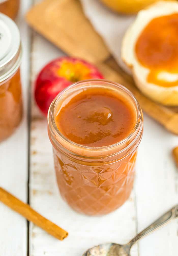 a jar of apple butter with fresh apples and cinnamon sticks