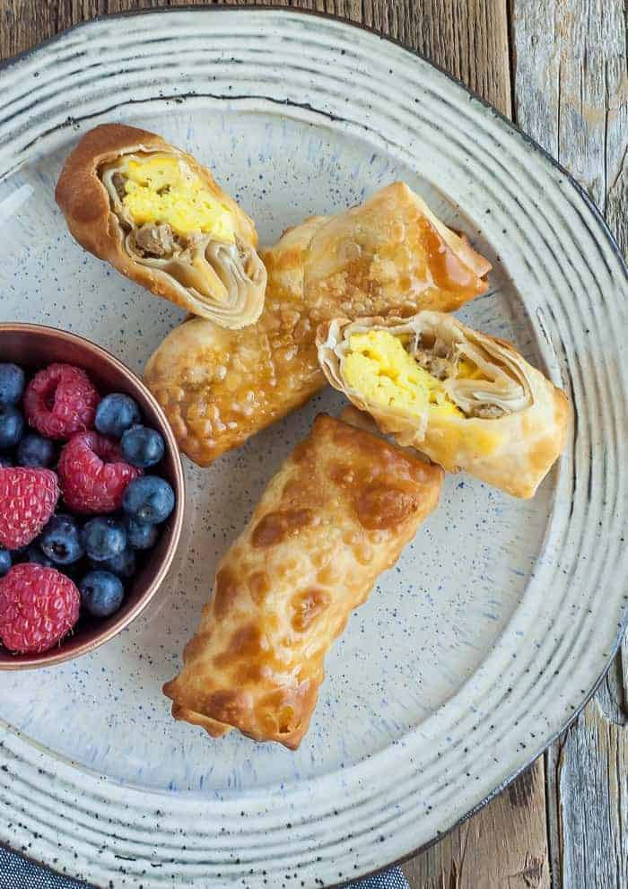 bacon and egg rolls on a grey plate with berries