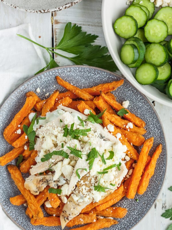 a plate of greek fries with sliced cucumbers