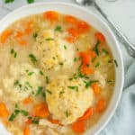 a bowl of instant pot chicken and dumplings with chopped parsley on top and a spoon
