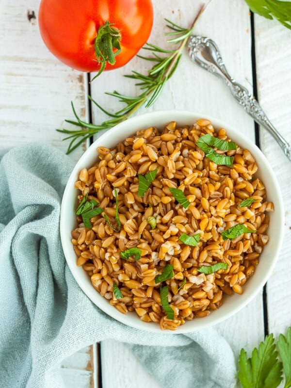 A white bowl with farro topped with chopped parsley