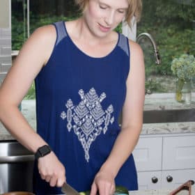 a woman in a blue top cutting a tomato