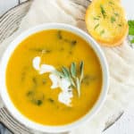 a bowl of vegan butternut squash soup with herbs and bread