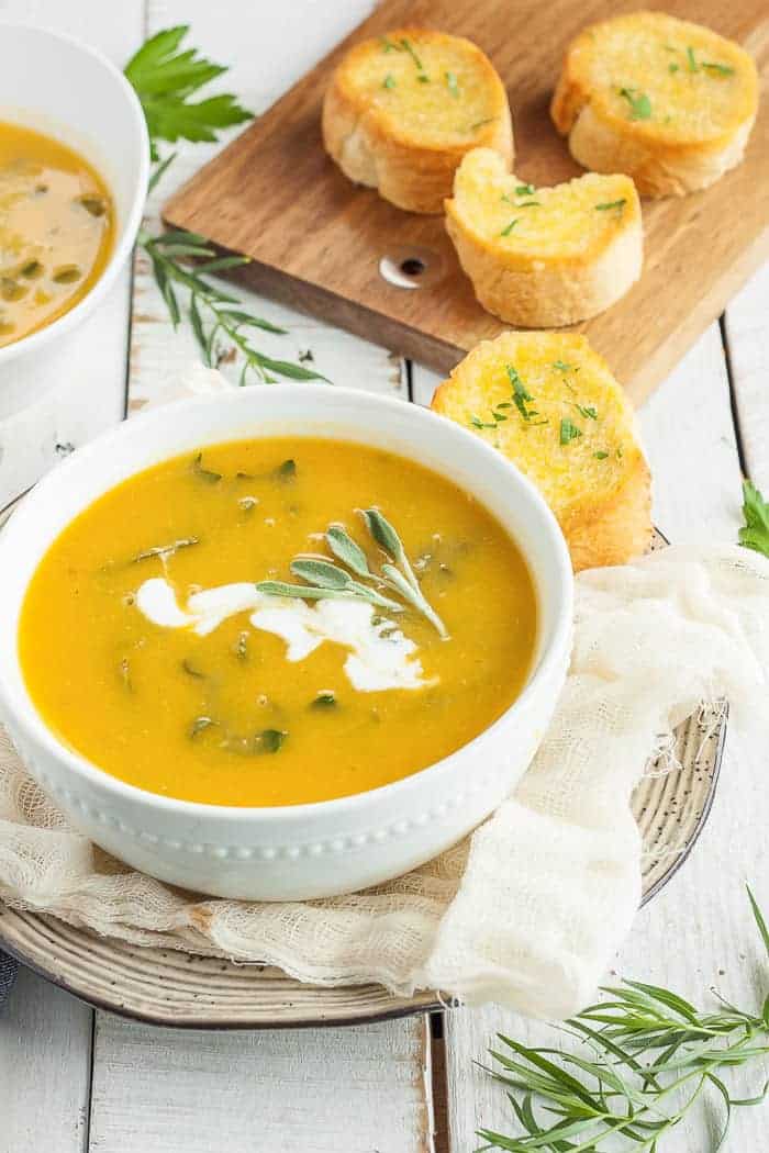 vegan butternut squash soup in a white bowl with fresh sage