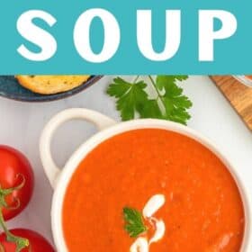 a bowl of tomato soup with a swirl of cashew cream and a sprig of parsley