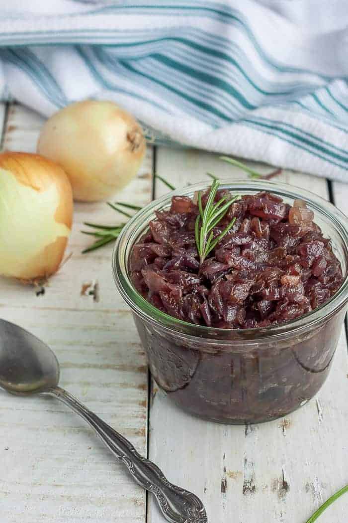 caramelized onions in a glass jar with rosemary and onions in the background
