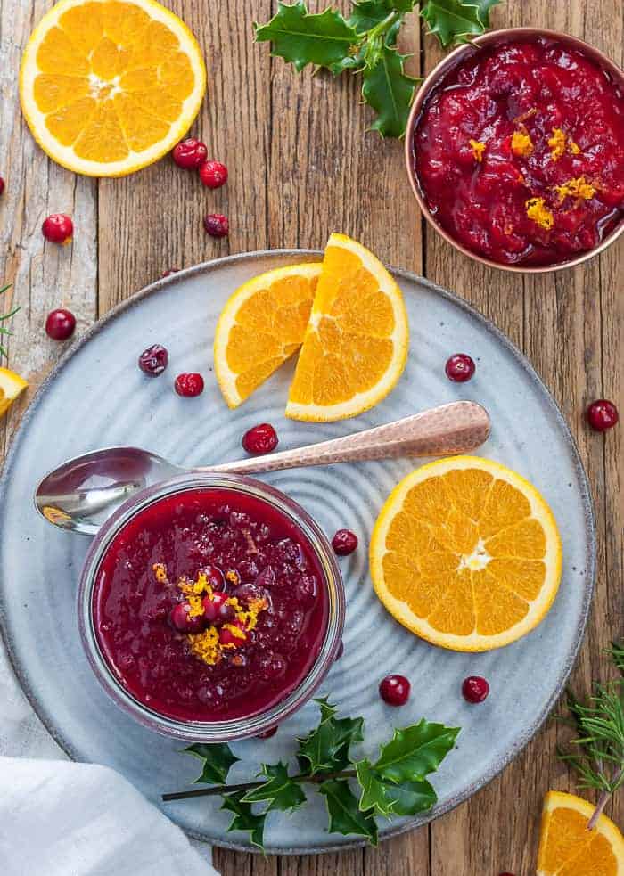 instant pot cranberry sauce in a glass jar on a plate with garnishes