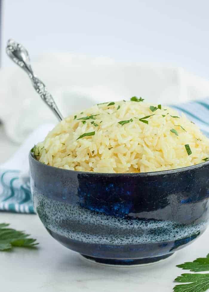 a side view of rice in a blue bowl topped with parsley