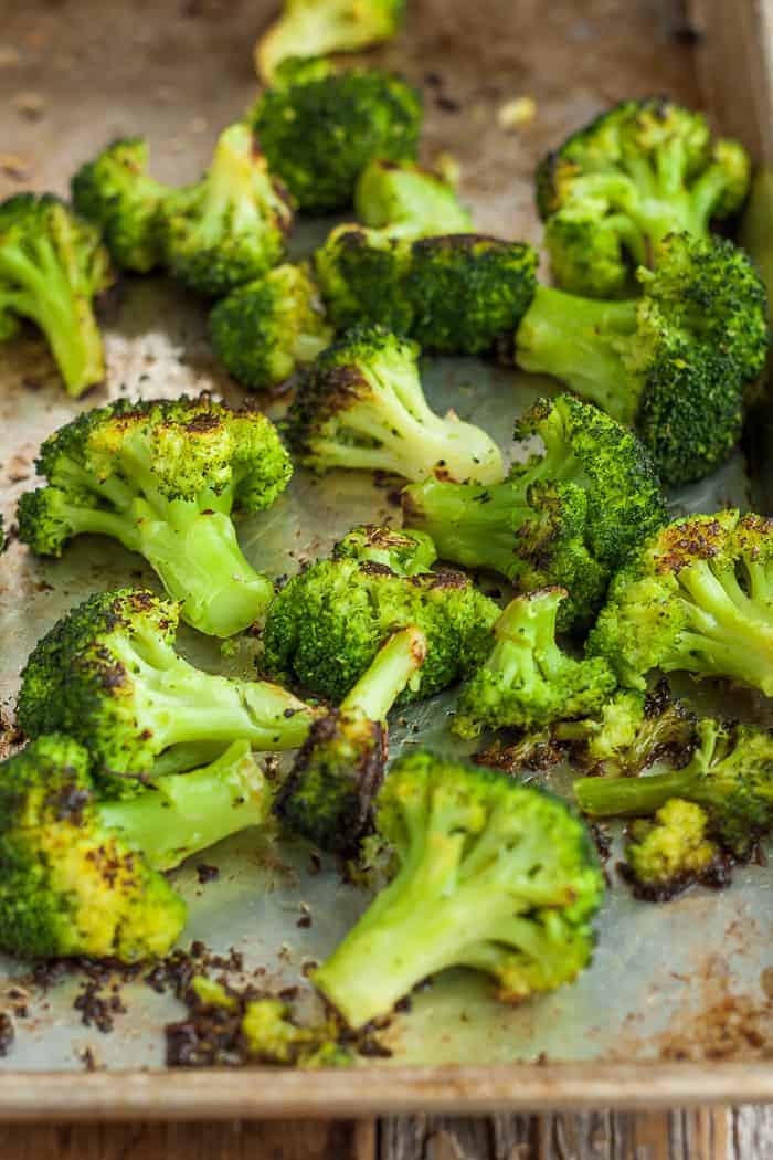 an upclose photo of roaste broccoli on a baking sheet