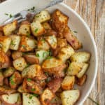 A bowl of crispy fried potatoes topped with parsley