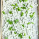 a baking sheet with chopped frozen onions on a piece of parchment